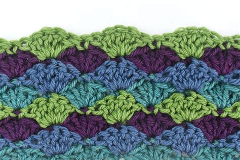 the crochet pattern is made up of two rows of green, blue and purple yarn