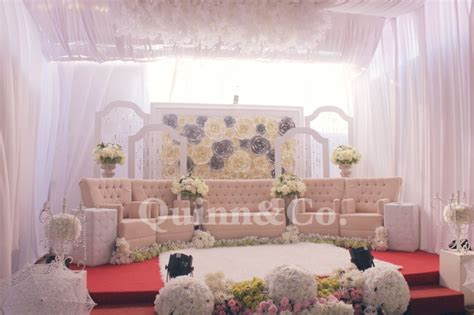 a decorated stage with white flowers and greenery on the floor for a wedding ceremony