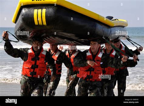 Navy SEAL candidates carry a raft during surf passage exercises on the first phase of training ...