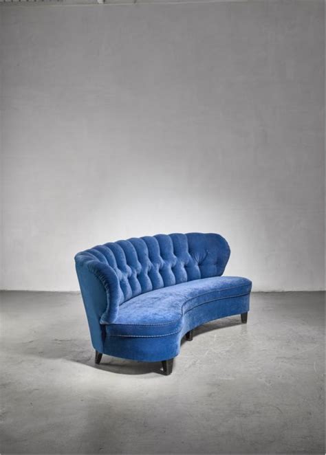 A curved sofa by Otto Schulz in royal blue velvet. The sofa stands on black lacquered wooden ...