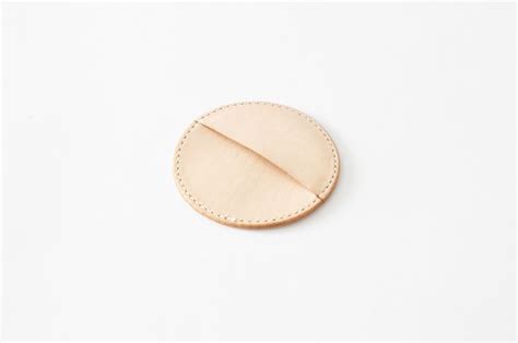 a wooden button with stitching on it sitting on a white surface in the shape of a circle