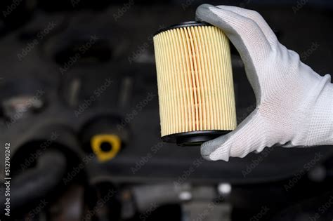 A new car oil filter on the background of the car, in the hand of an ...