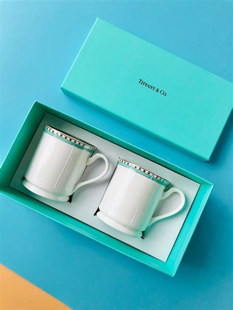 two white coffee mugs sitting in a blue box