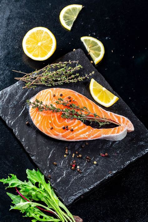 Fresh salmon steak on a black stone tray with spices and lemon slices - Creative Commons Bilder
