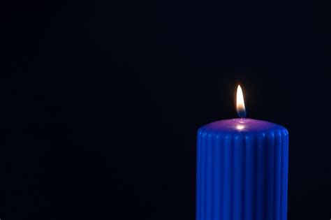 Premium Photo | Blue purple candle with orange flame over black background