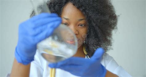 Side Portrait of the Happy Smiling African Female Research Scientist Observing the Round-bottom ...