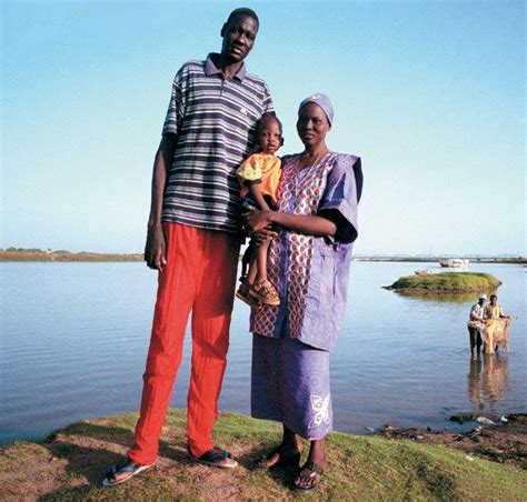 a man and woman standing next to each other on the shore of a body of water