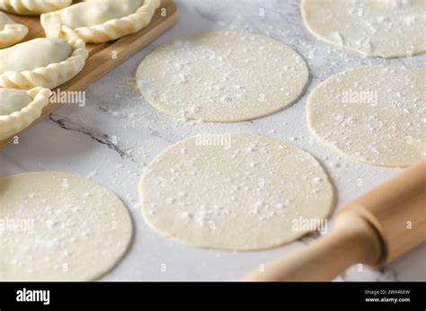 Circled dough for making Argentinian empanadas on a white marble ...