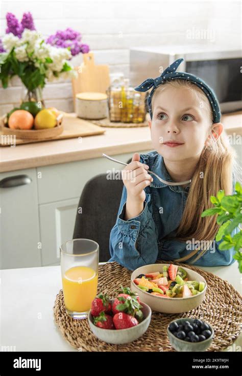 Healthy food at home. Cute little girl eats fruit salad Stock Photo - Alamy