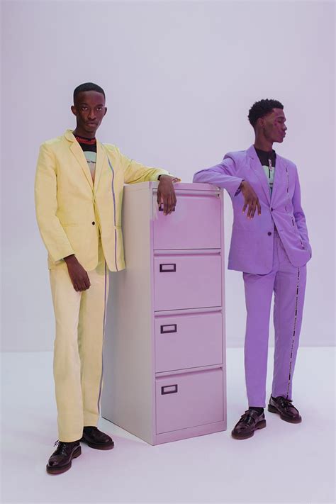 two men in suits standing next to a pink filing cabinet with their hands on the drawers