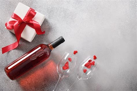 Premium Photo | Valentine's day card with red wine and gift on gray background.