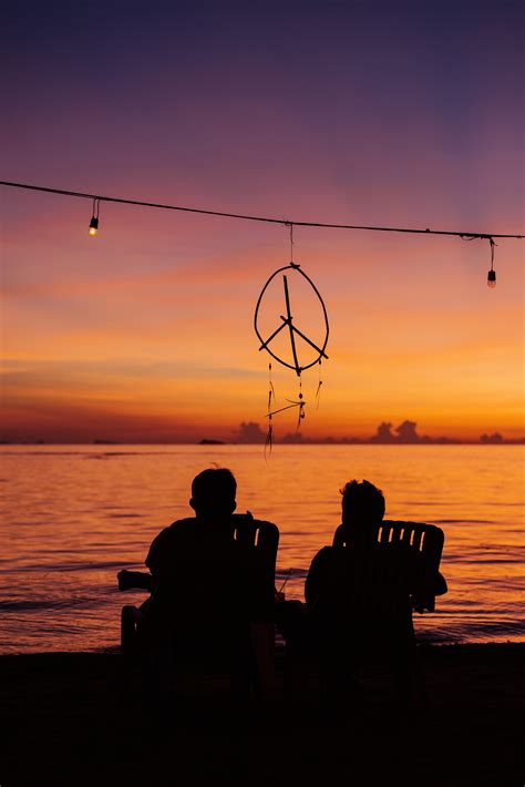 Silhouette of Two People Sitting on the Beach during Golden Hour · Free ...