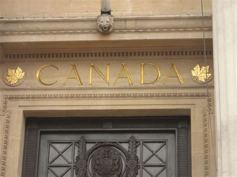 the front door to an old building with gold lettering on it's sides and leaves