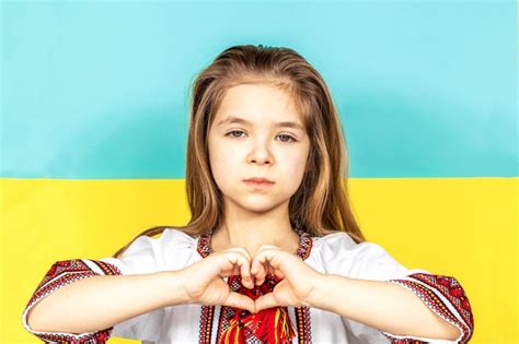 Premium Photo | A girl in an embroidered shirt shows a heart sign as a sign of love for ukraine