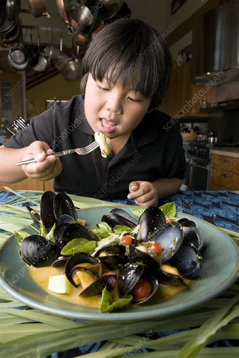 Boy eating mussels - Stock Image - P920/0801 - Science Photo Library