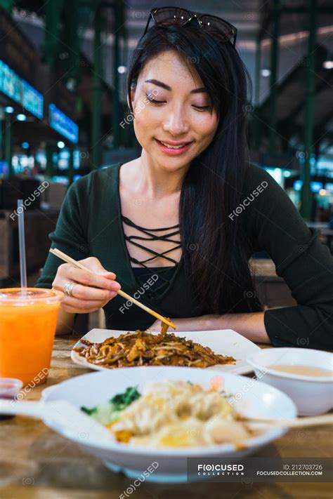 Young asian woman eating food with chopsticks — chilling, attractive ...