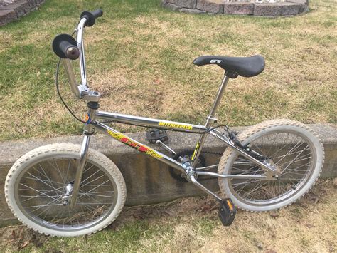 a bicycle parked on the side of a stone wall in front of grass and rocks