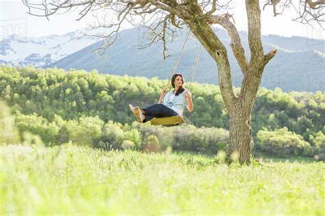 Caucasian woman swinging on tree swing - Stock Photo - Dissolve