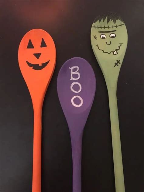 three spoons decorated with halloween designs on black table top, one for boo and the other for ...