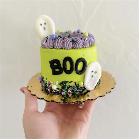 a hand holding a cake decorated with halloween decorations