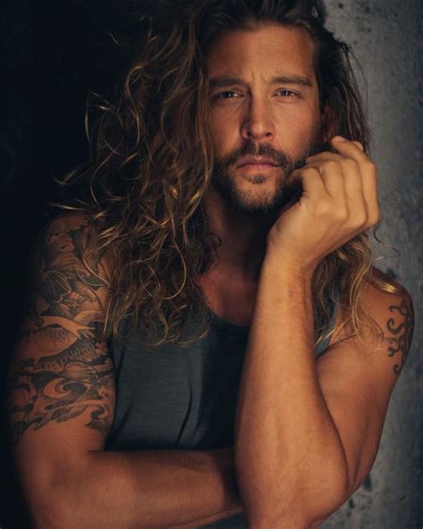 a man with long hair and tattoos on his arms