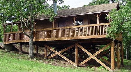 a large wooden house sitting on top of a lush green hillside next to a forest