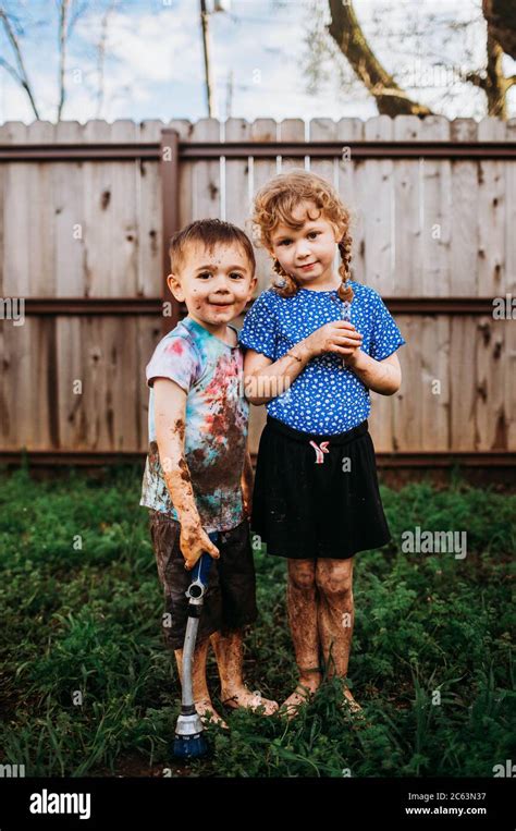 Two young kids playing in muddy backyard in spring Stock Photo - Alamy