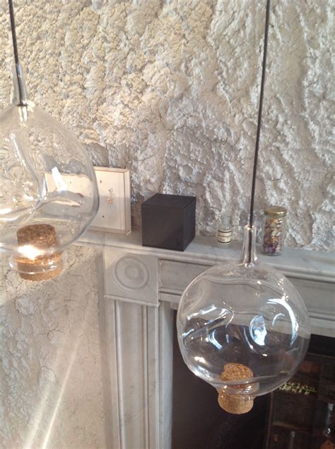 two clear glass lamps hanging over a fireplace