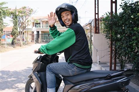 Premium Photo | Back view of happy commercial motorcycle taxi driver wearing helmet and uniform ...