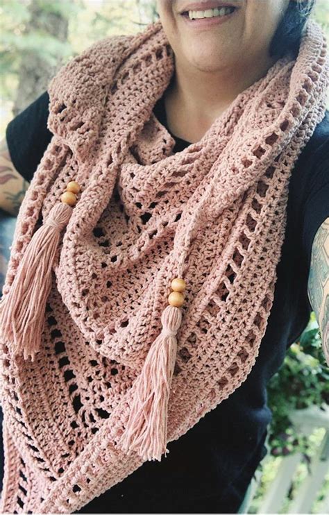 a woman wearing a pink crocheted scarf with tassels and beads on it