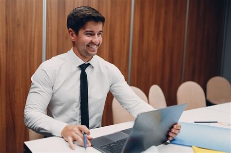 Premium Photo | Young businessman with laptop at table in office video conference call web cam ...