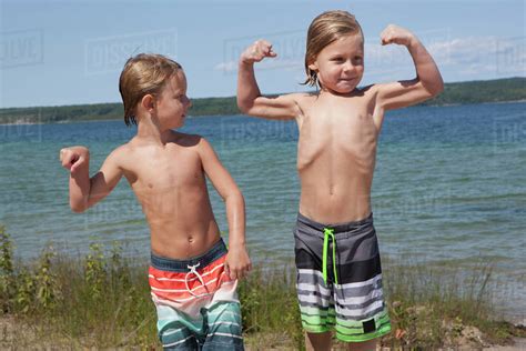 Caucasian boys flexing muscles on beach - Stock Photo - Dissolve