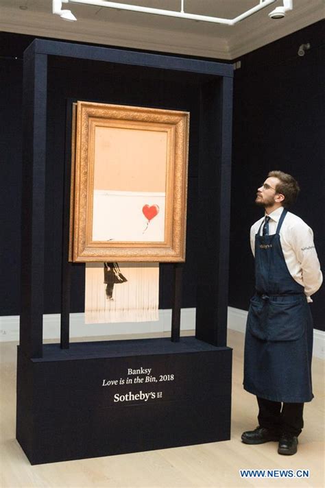 Sotheby's staff members present Banksy's "Love is in the Bin" in London ...