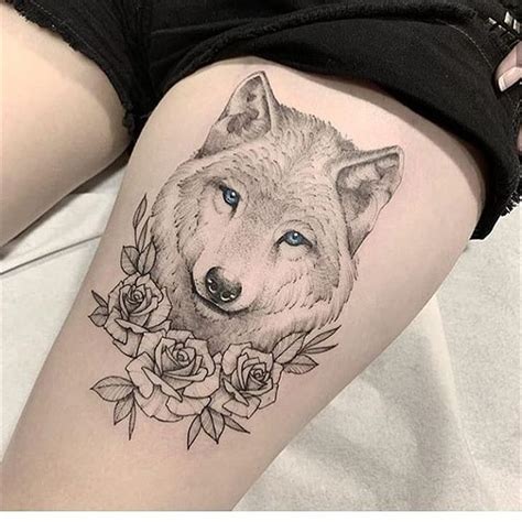 a woman's thigh with a wolf and roses tattoo on it