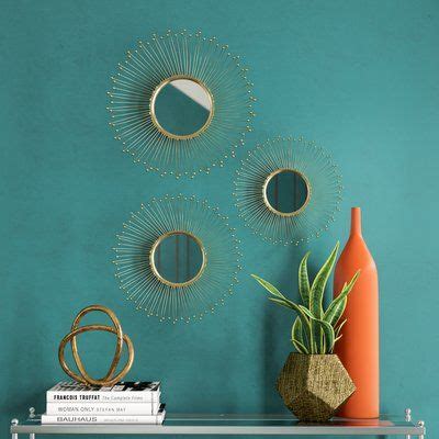 three circular mirrors are hanging on the wall above a shelf with books and a vase