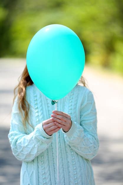 Premium Photo | Girl holding balloon near face