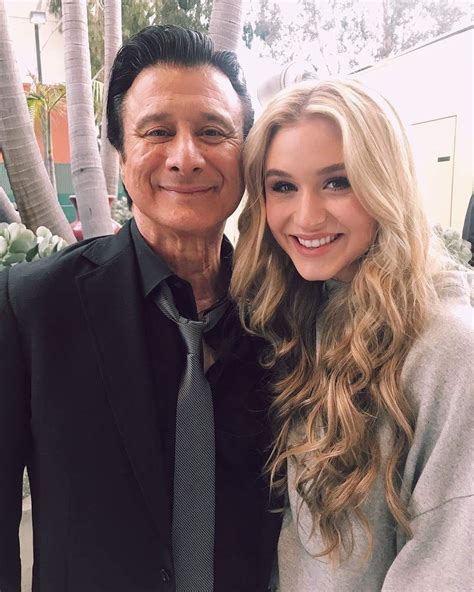 a woman standing next to a man in a black suit and gray tie smiling at the camera