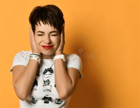 Portrait of Woman with Short Haircut and in White T-shirt Standing with Closed Eyes Covering Her ...