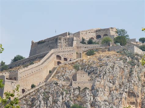 an old castle perched on top of a rocky hill with trees growing out of it