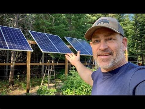 a man standing in front of a row of solar panels on top of a forest