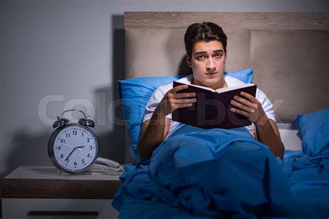 Young man reading book in bed | Stock image | Colourbox