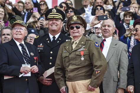 World War II veterans, service members and other attendees watch a flyover of military aircraft ...