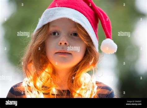 A little girl dressed in a santa hat and fairy Christmas lights Stock Photo - Alamy