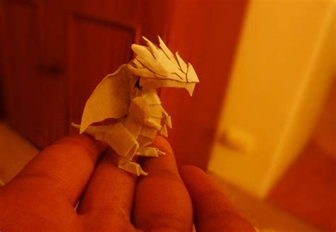 a hand holding a small white origami animal