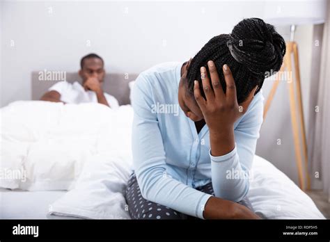 Close-up Of Sad Woman Sitting On Bed In Front Of Her Husband Stock Photo - Alamy