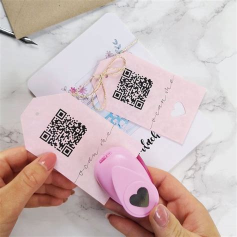 someone is holding two pink tags with a qr code on one and a heart on the other