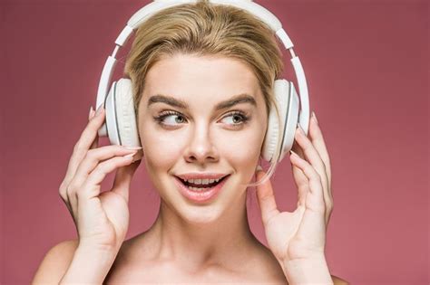 a woman with headphones on her ears smiling at the camera, against a ...