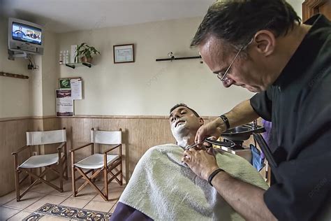 Barber Using A Straight Razor To Shave A Young Man In A Traditional ...