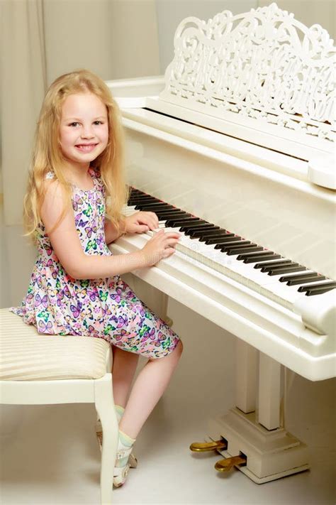 Beautiful Little Girl is Playing on a White Grand Piano. Stock Image ...