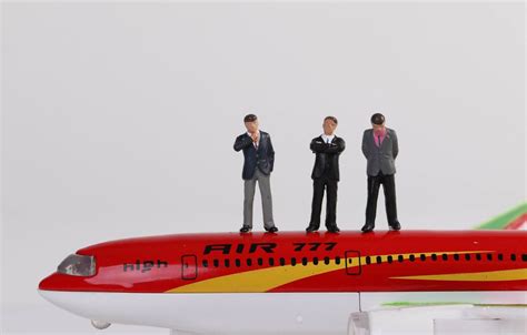 Miniature travelers standing on a red airplane with globe in the background - Creative Commons ...